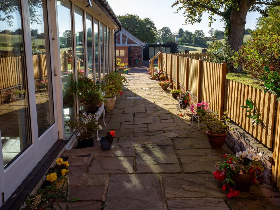 An outdoor area with a slate pathway and flower pots at Nature's Lodge in Kidderminster