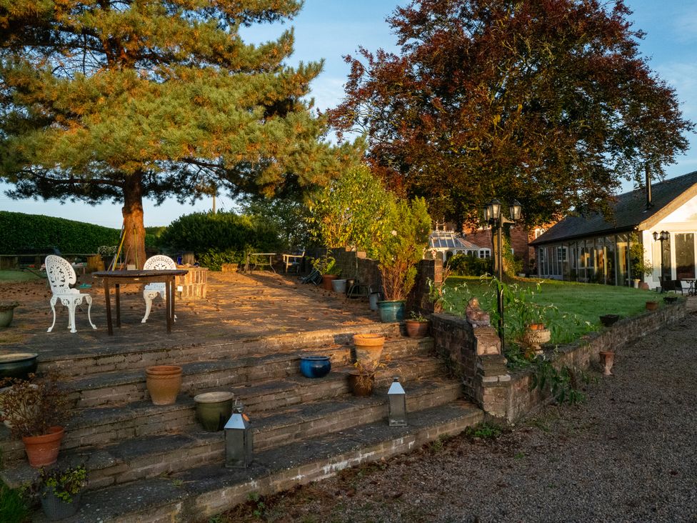 A garden with a table and chairs near a tree at Nature's Lodge in Kidderminster