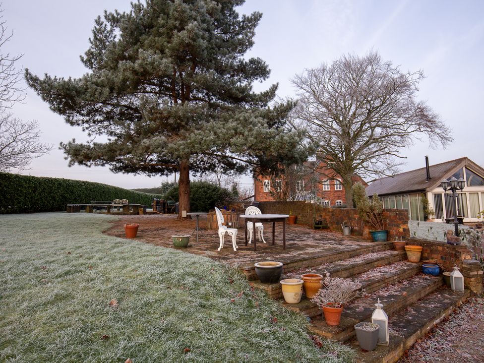 A garden with a table and chairs beside trees at Nature's Lodge in Kidderminster