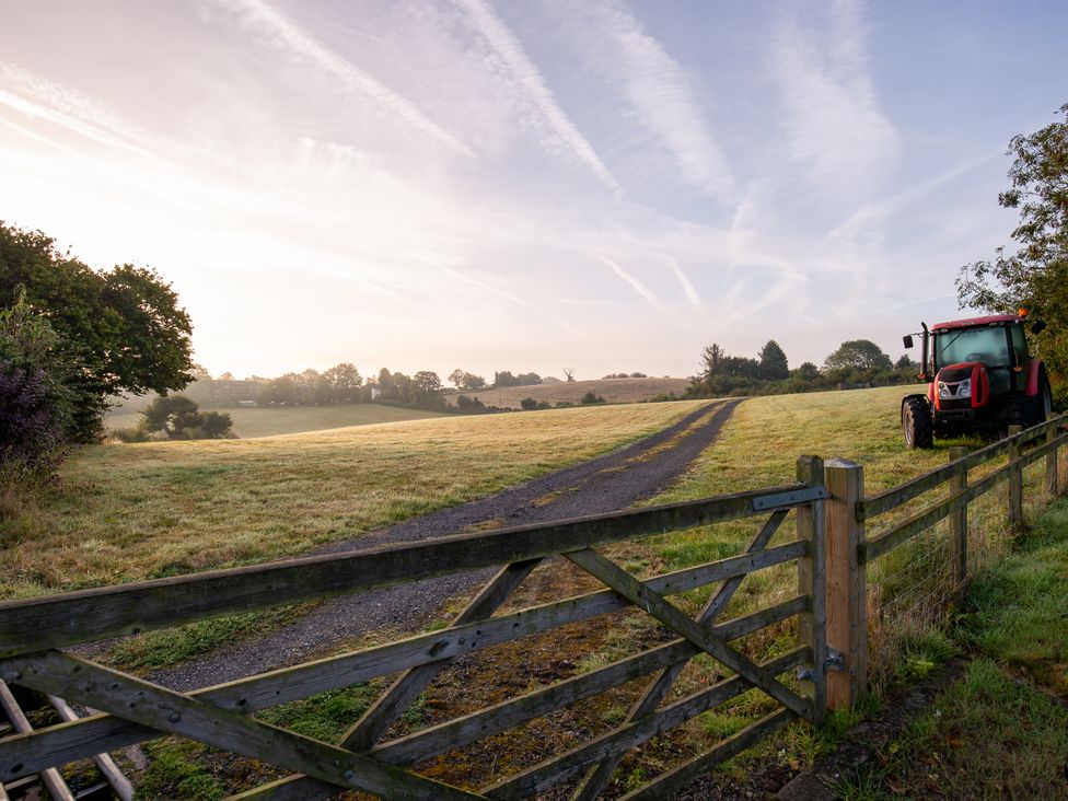 A field with a tractor and a wooden fence at Nature's Lodge in Kidderminster