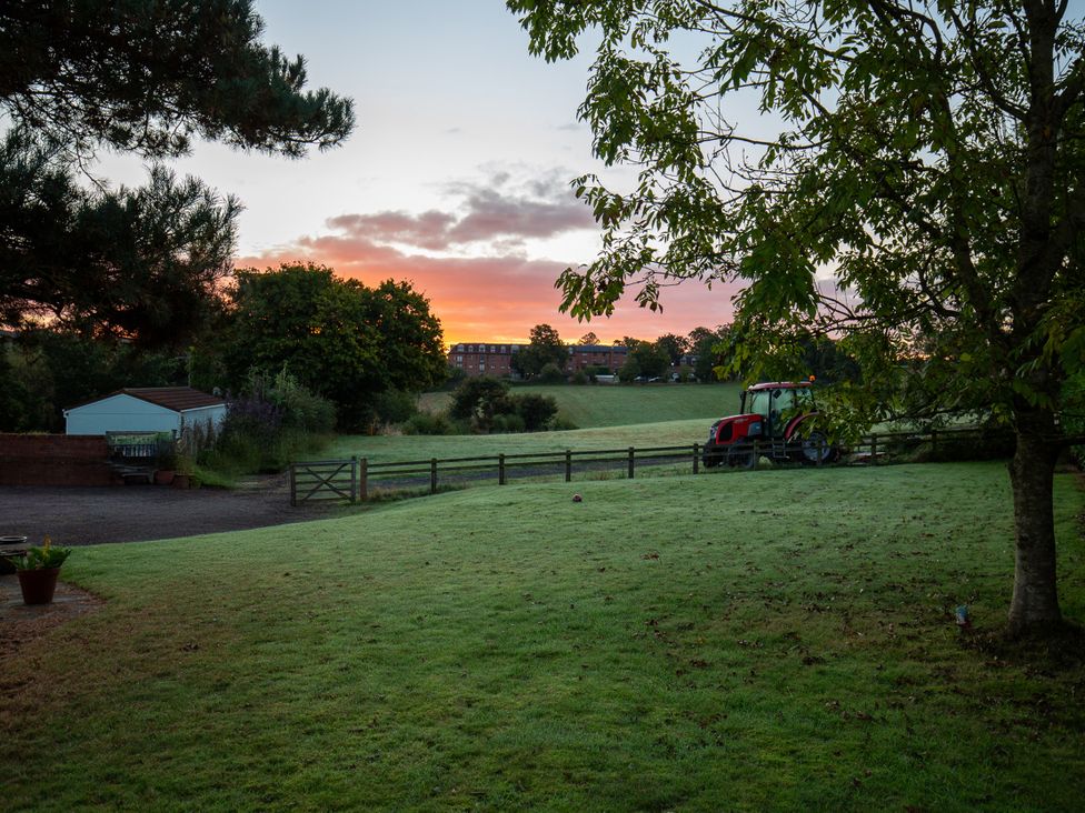 A lawn with a tractor and a shed at Nature's Lodge in Kidderminster