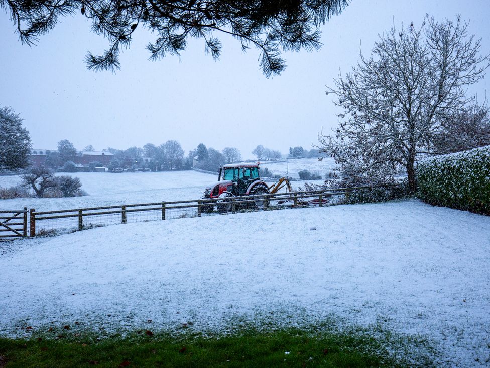 A tractor in snow with a fence and trees at Nature's Lodge in Kidderminster