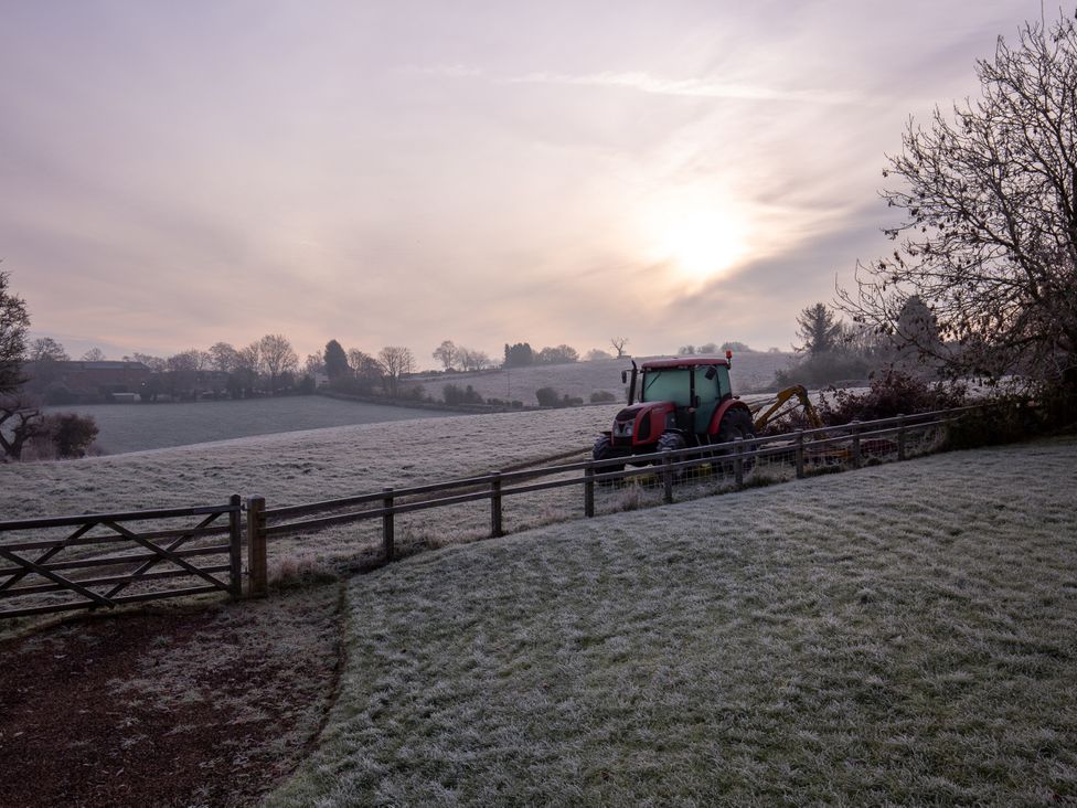 A tractor in a field during sunrise at Nature's Lodge in Kidderminster