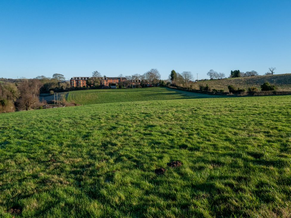 A field with grass and trees near a building at Nature's Lodge in Kidderminster
