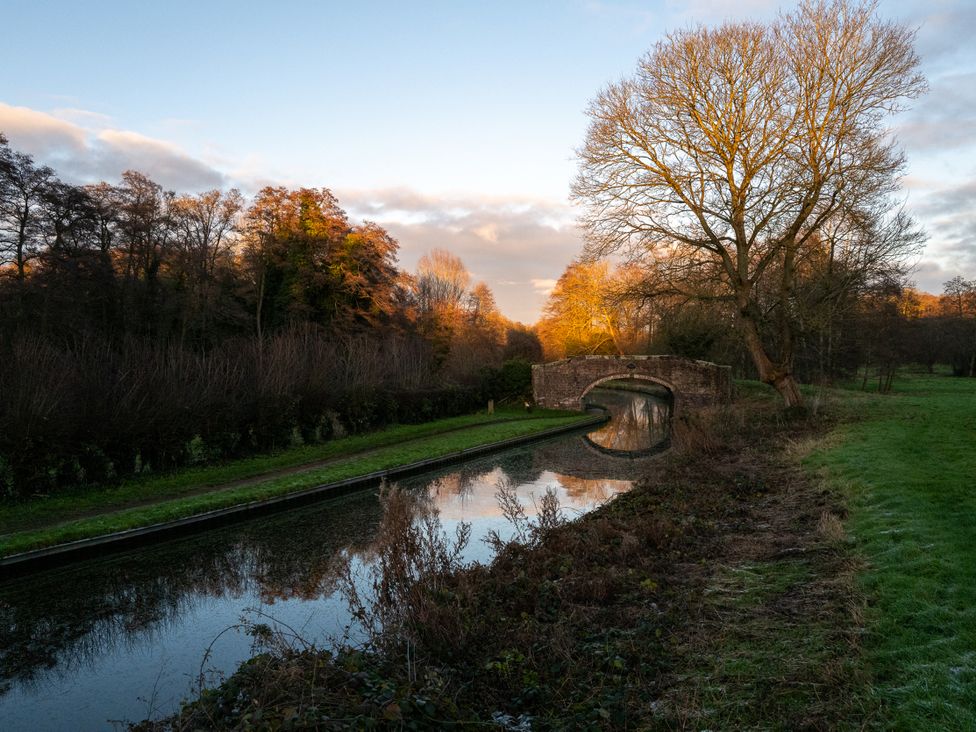 A canal with a bridge and trees at Nature's Lodge in Kidderminster