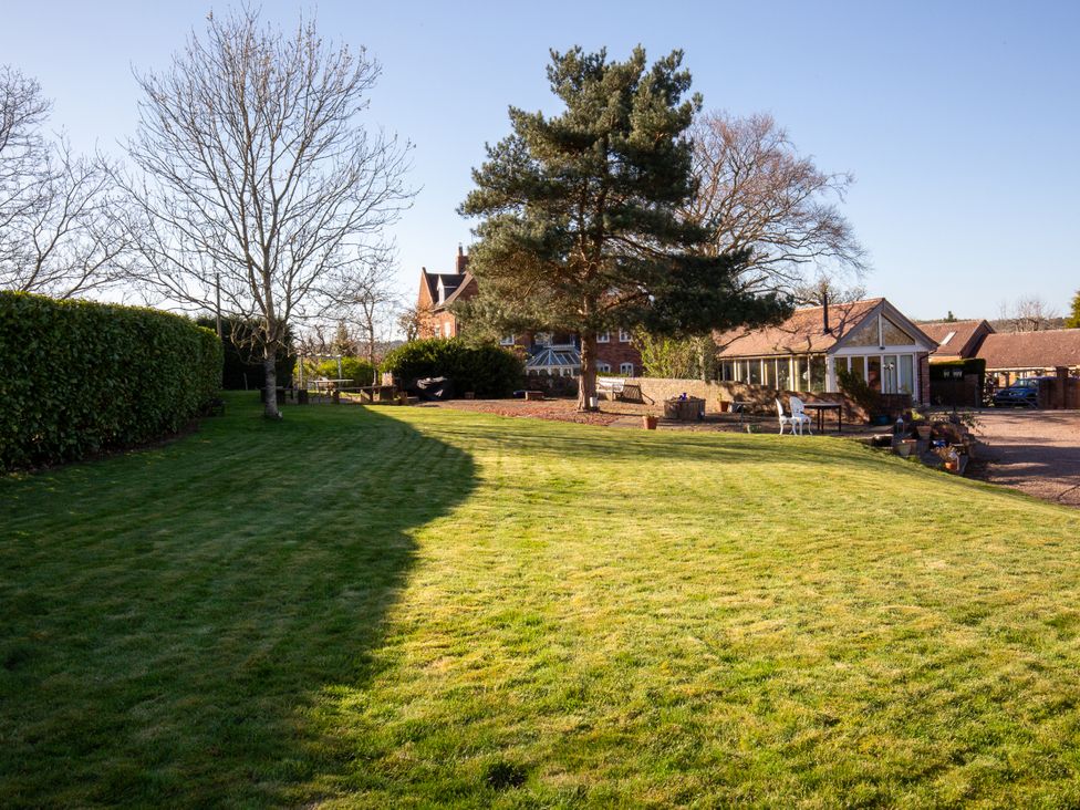 A garden with grass, trees, and seating areas at Nature's Lodge in Kidderminster