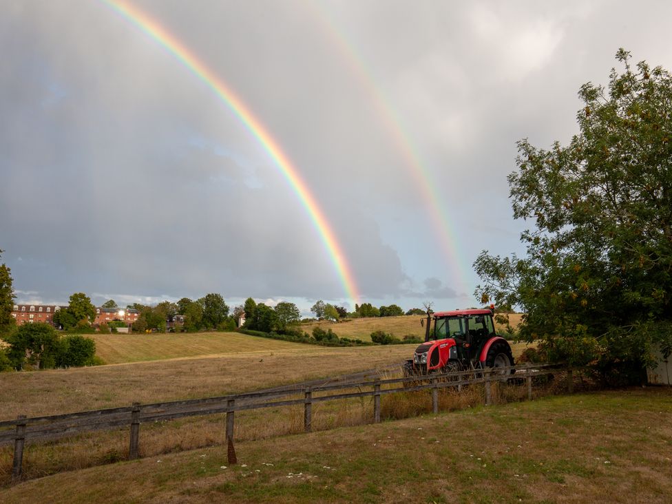 A tractor in a field with a rainbow at Nature's Lodge in Kidderminster