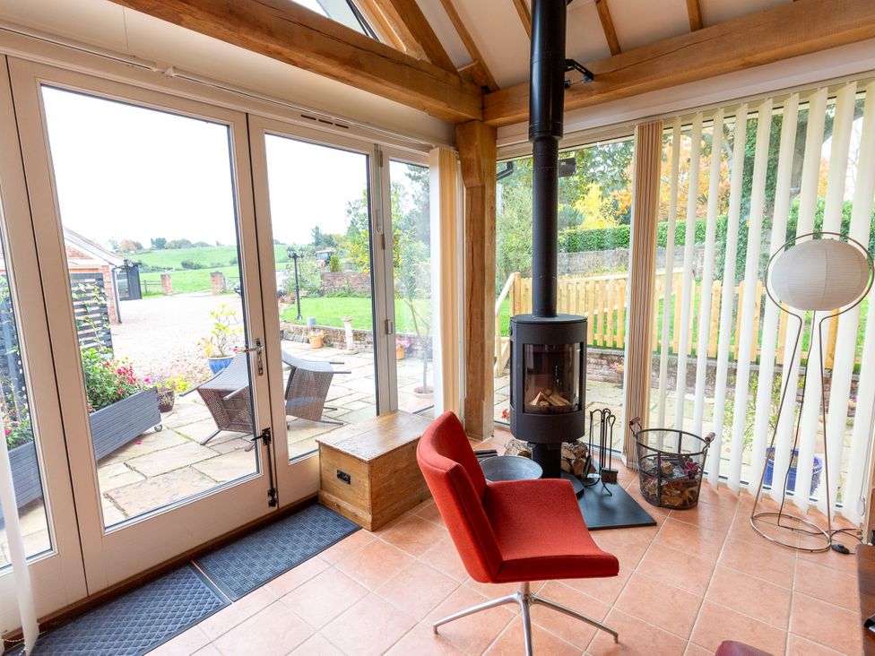 A conservatory with a fireplace and red chair at Nature's Lodge in Cookley