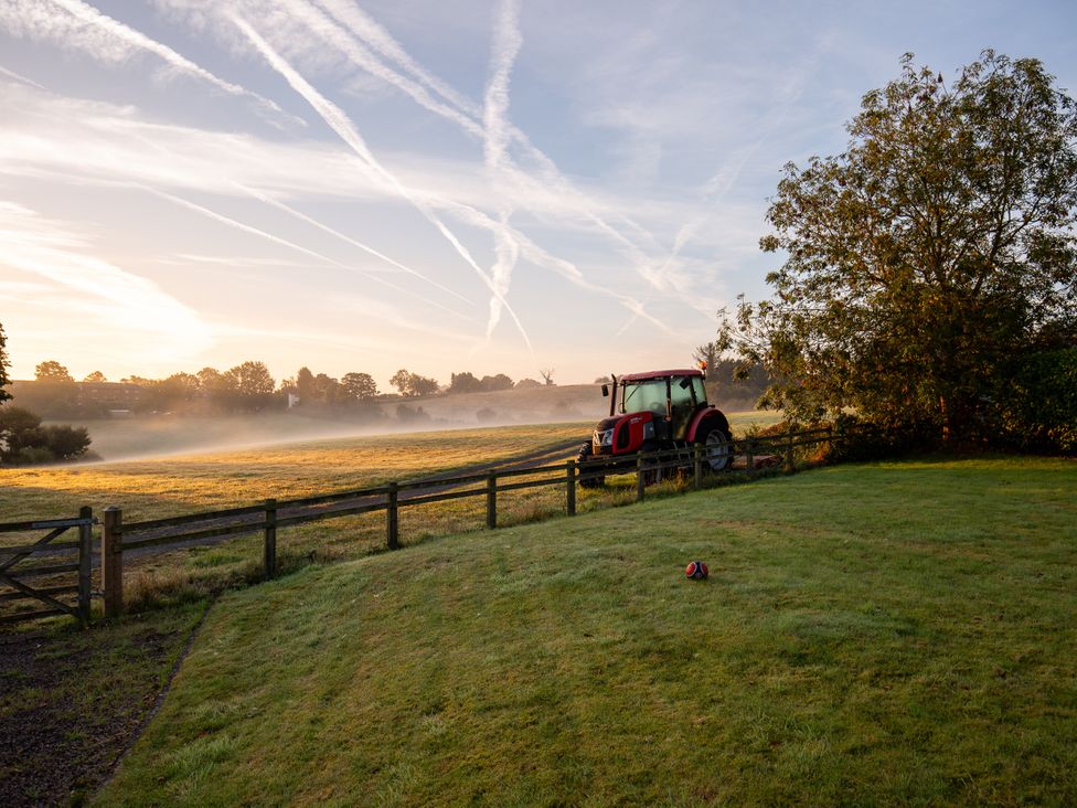 A tractor near a fence and tree in a field at Nature's Lodge in Cookley