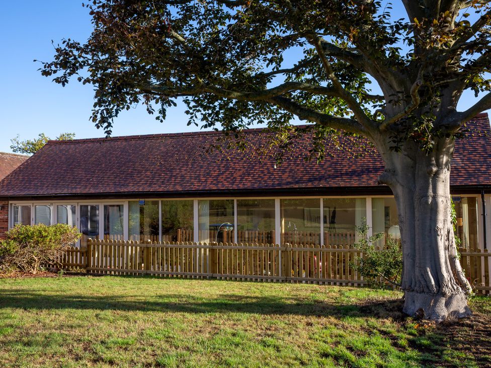 A house with a fence and tree at Nature's Lodge in Cookley