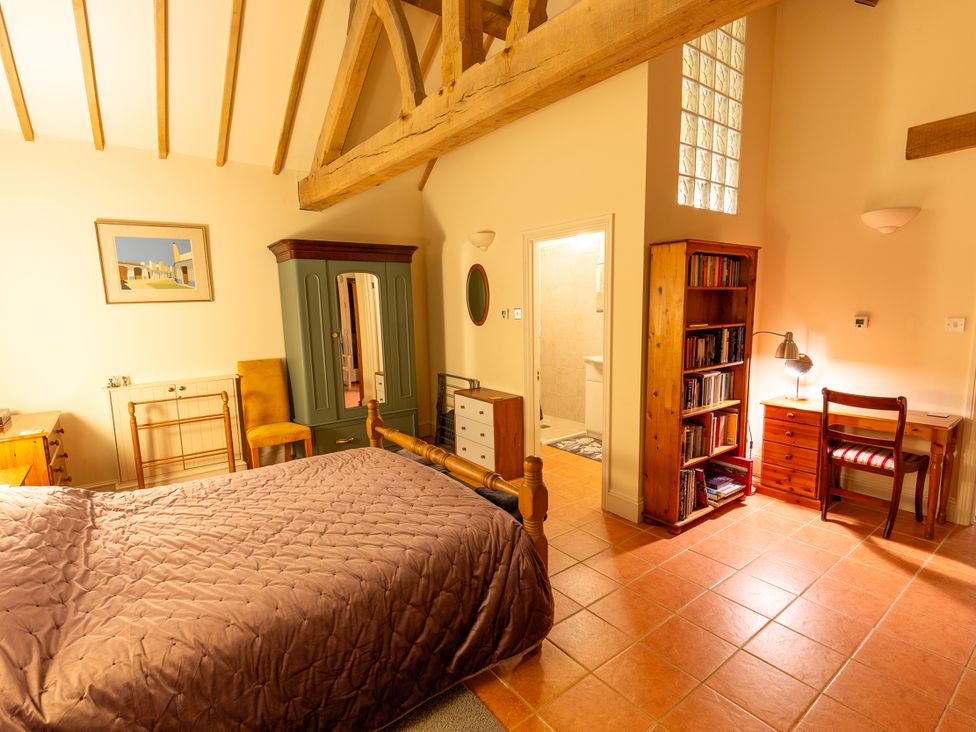 A bedroom with a bed, wardrobe, chair, desk and bookshelf at Nature's Lodge in Cookley