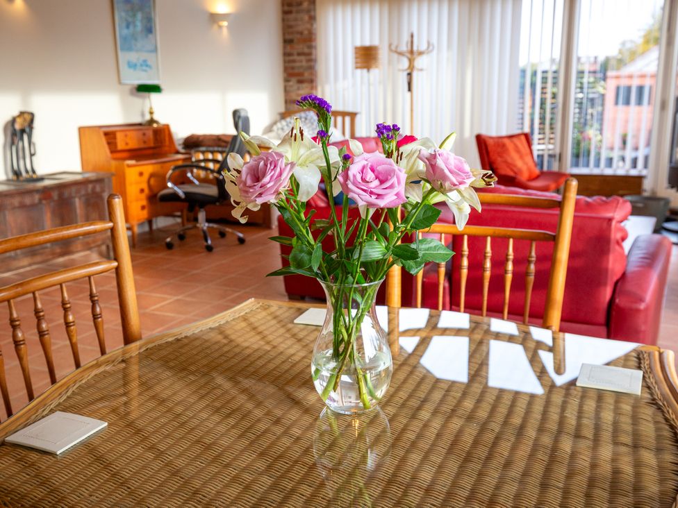 A dining room with a table and flowers at Nature's Lodge in Cookley
