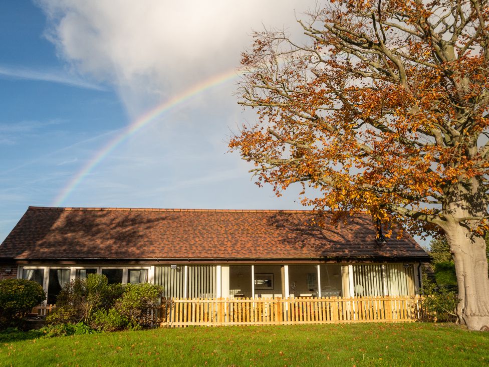 A house with a fence and tree under a rainbow at Nature's Lodge in Cookley