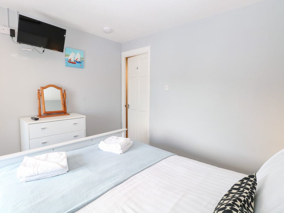 A bedroom with a bed and a mirror at Cotman Cottage in Hoveton & Wroxham