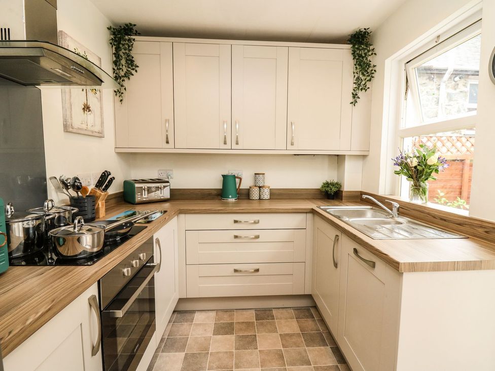 A kitchen with cabinets, sink, and cooking pots at 6 Upperfield Street Dolgellau