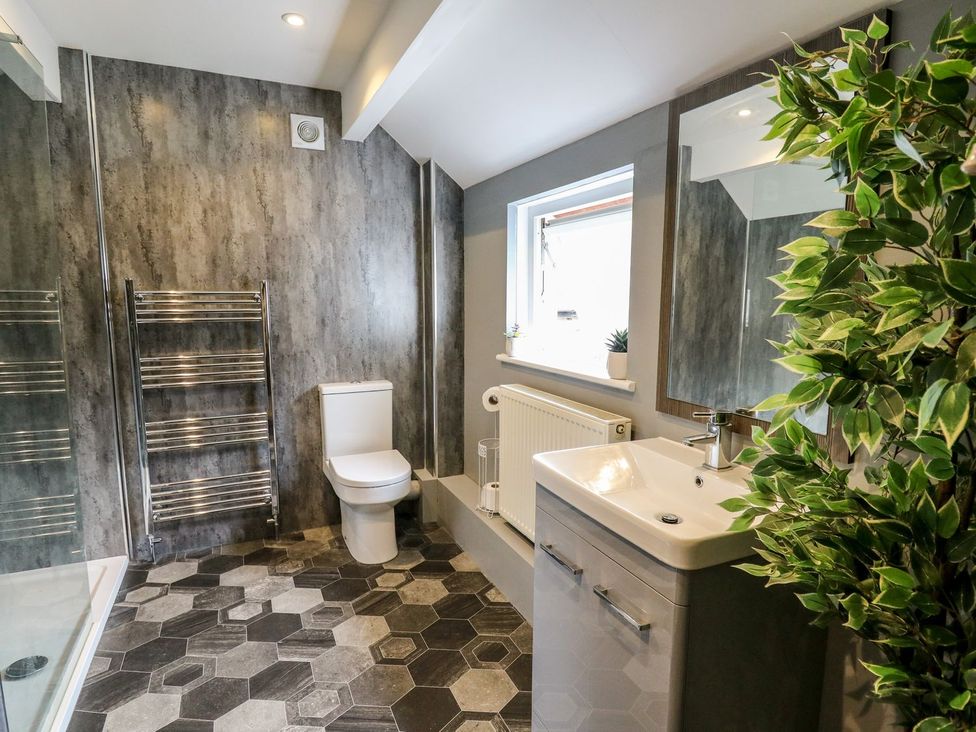 A bathroom with a sink, toilet, shower and hexagonal floor tiles at 6 Upperfield Street in Dolgellau