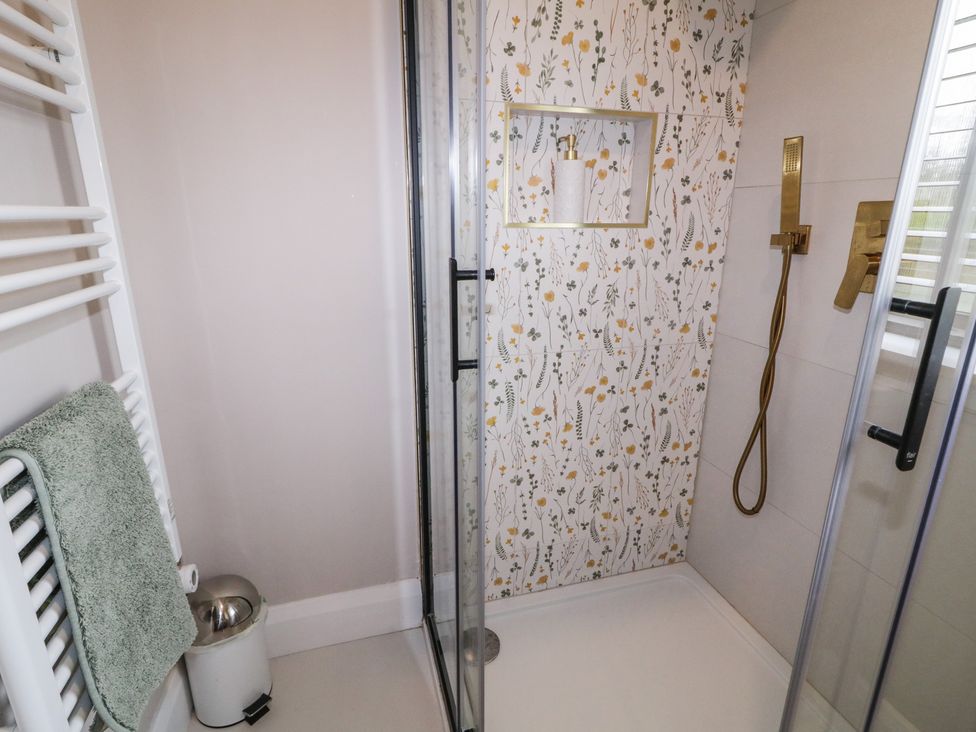 A shower with floral tiles and towel rail at Lake view House Apartment