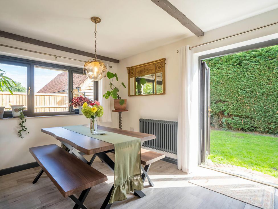 A dining area with a table and benches at Foxley Lodge in Norwich