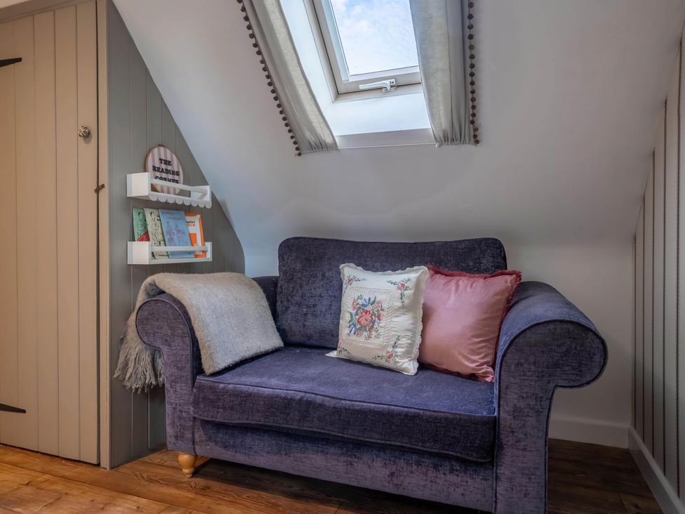 A snug room with a purple armchair and a shelf with books at Foxley Lodge in Norwich