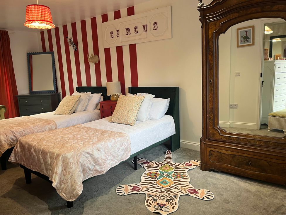 A bedroom featuring two beds with a rug and an antique mirror at Foxley Lodge in Norwich