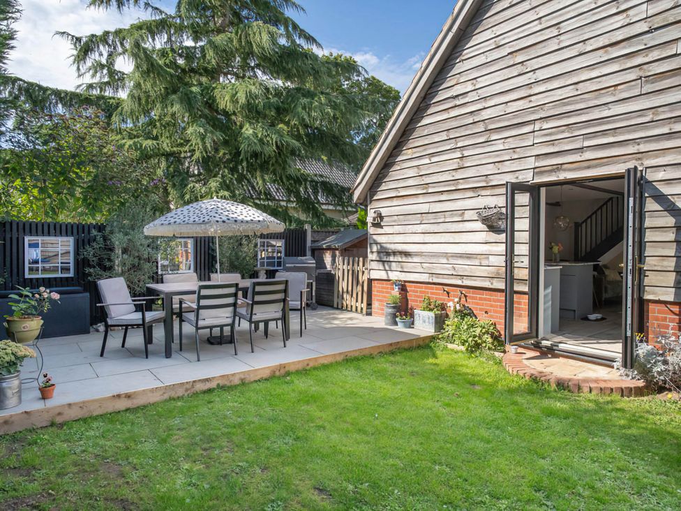 A garden with a dining set and an umbrella at Foxley Lodge in Norwich