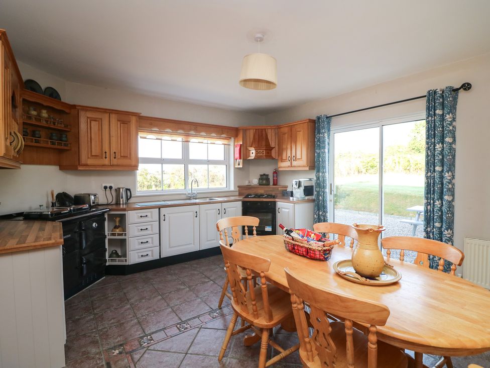 A kitchen with wooden cabinets and a dining table at The Lodge Bolinahaney Bunclody, County Wexford
