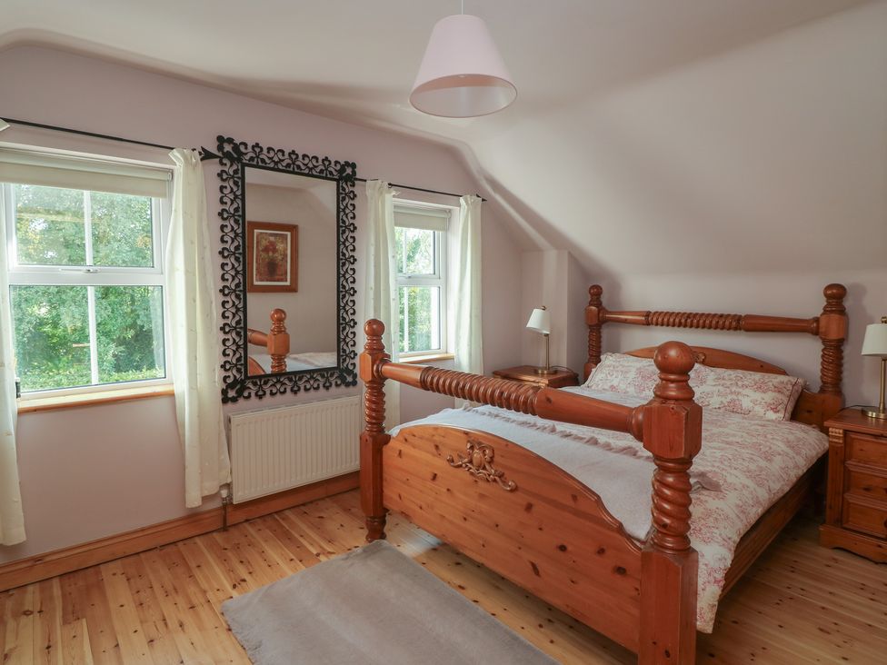 A bedroom with a wooden bed and lamp at The Lodge Bolinahaney in Bunclody, County Wexford