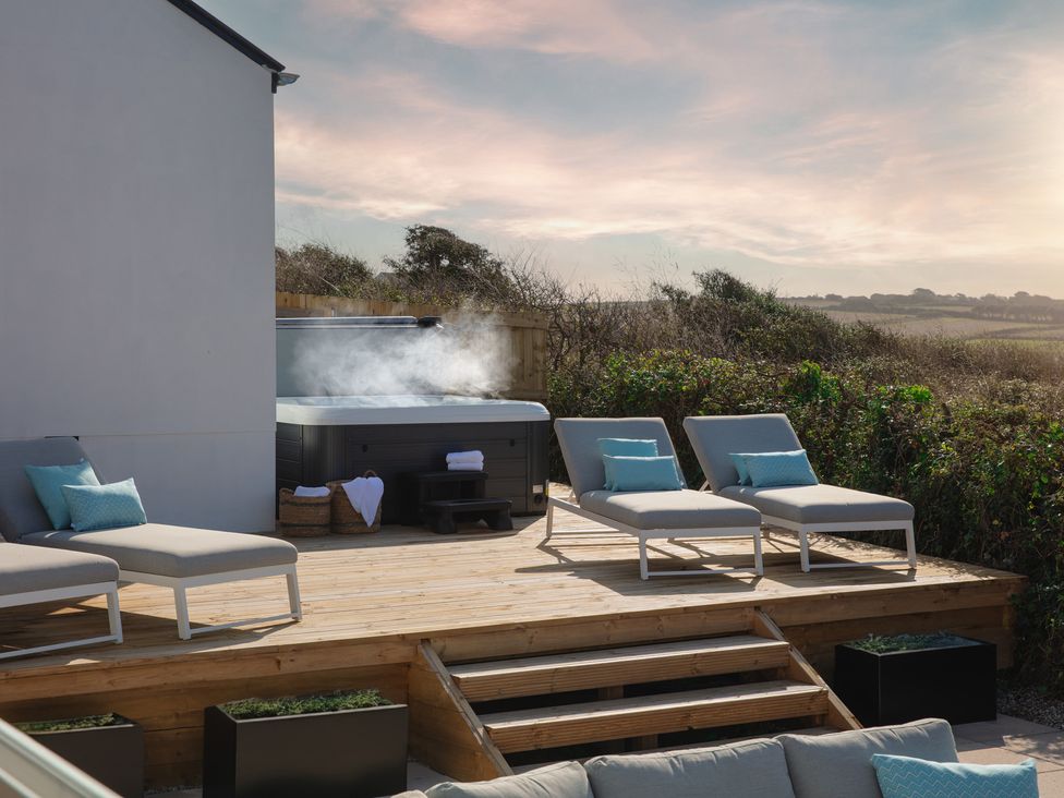 A hot tub and loungers on a wooden deck at Polview in Newquay