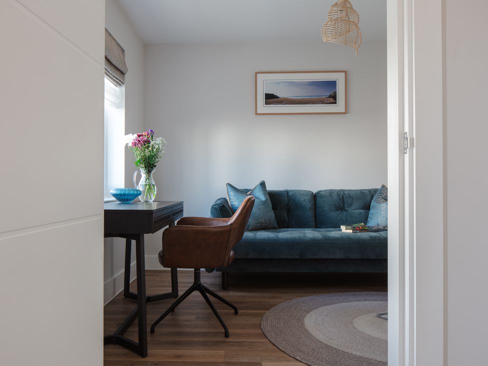 A living room with a sofa, chair, and a vase with flowers at Polview in Newquay