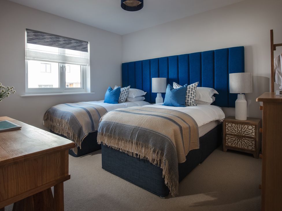 A bedroom with two beds and a table at Polview in Newquay