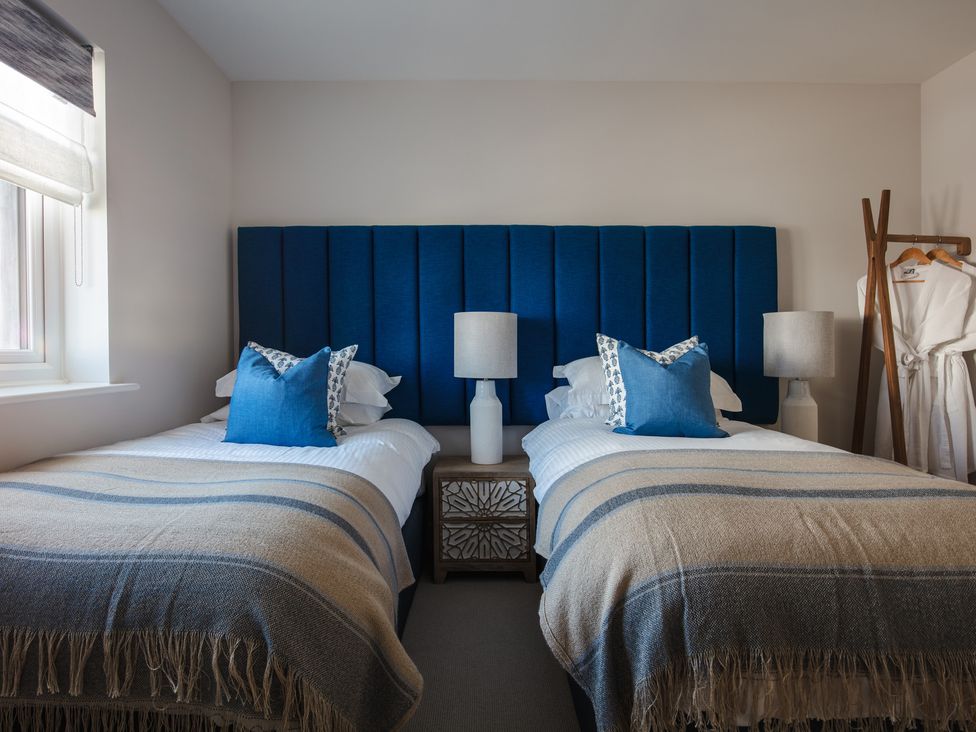 A bedroom with two beds and lamps at Polview in Newquay