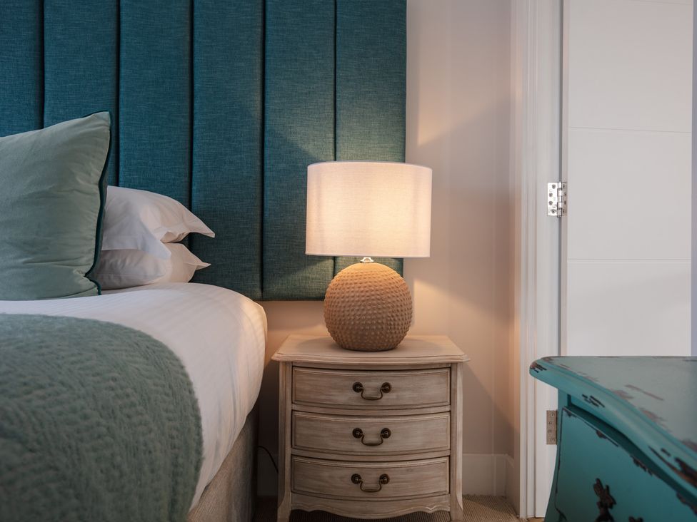 A bedroom with a bed and a lamp on a nightstand at Polview in Newquay