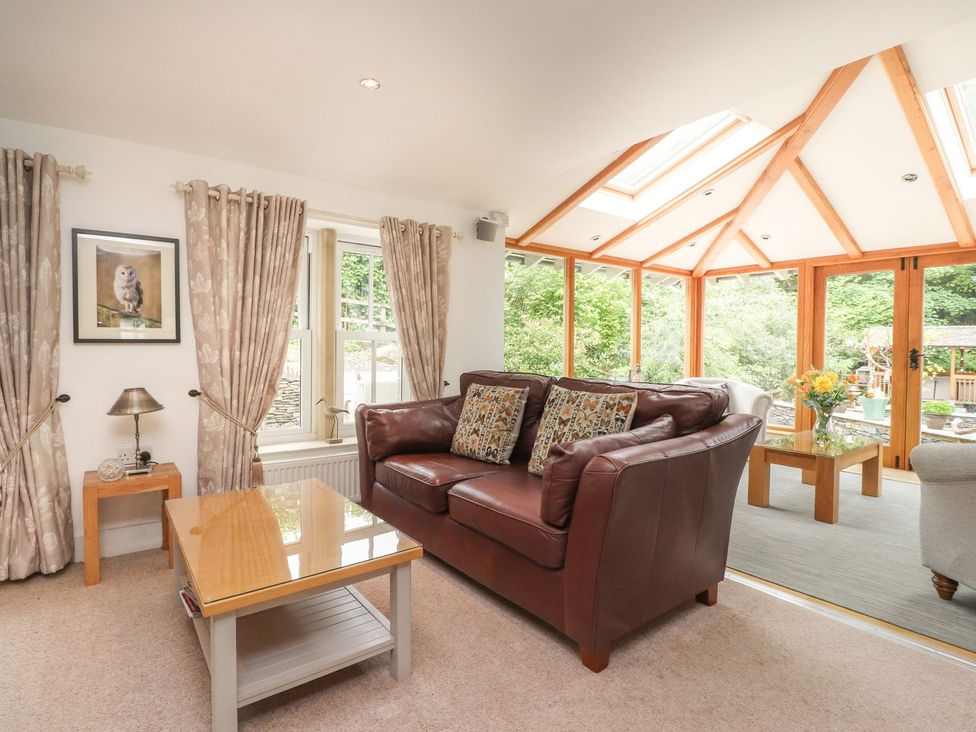 A conservatory with a sofa and coffee table at Bobbin Mill Cottage in Ulverston