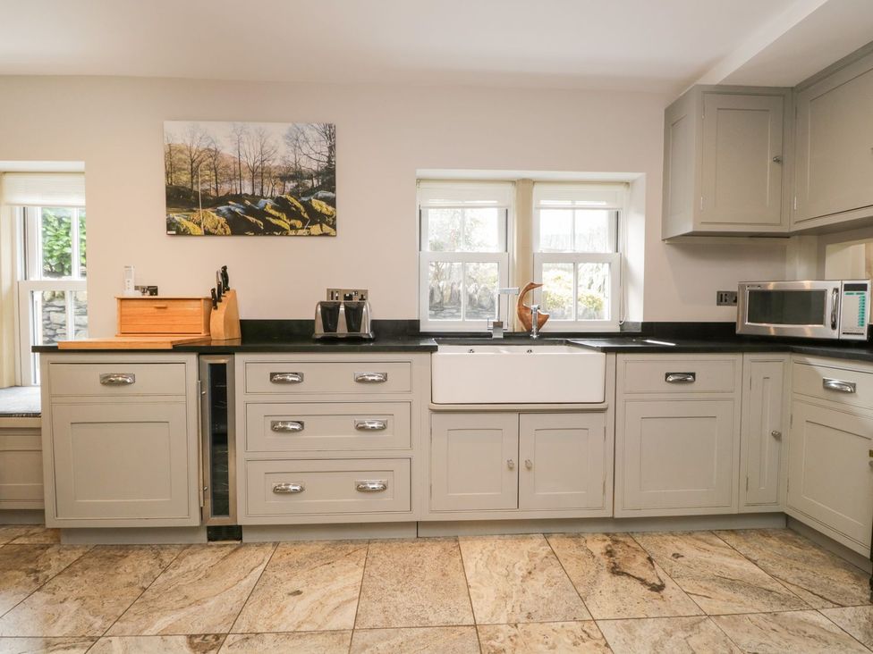 A kitchen with cabinets, sink, and microwave at Bobbin Mill Cottage, Ulverston