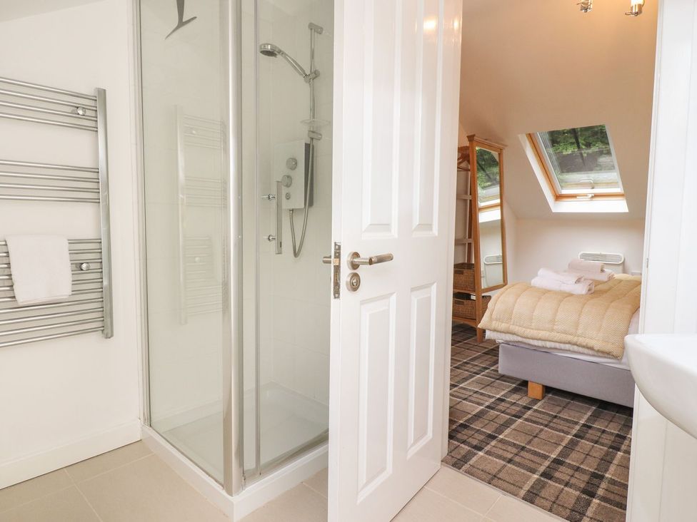 A bathroom with a shower and bed area at Bobbin Mill Cottage in Ulverston