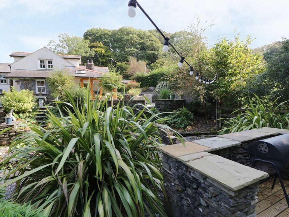 A garden with a stone wall and a grill at Bobbin Mill Cottage in Ulverston