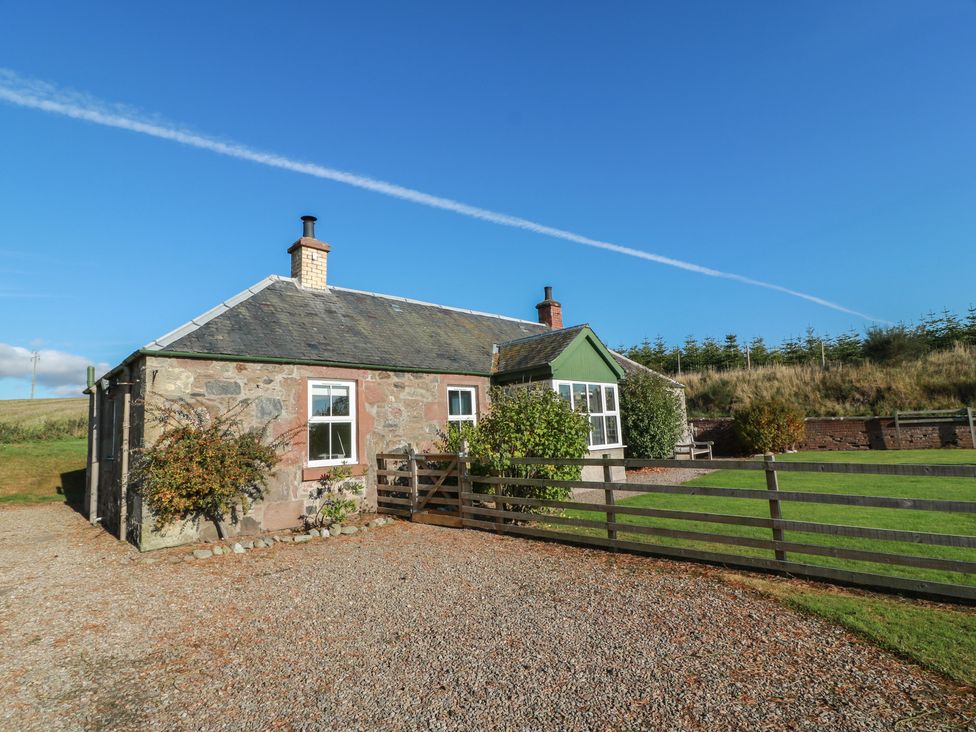 A cottage with a fence and garden area at Clayhills Cottage in Blairgowrie
