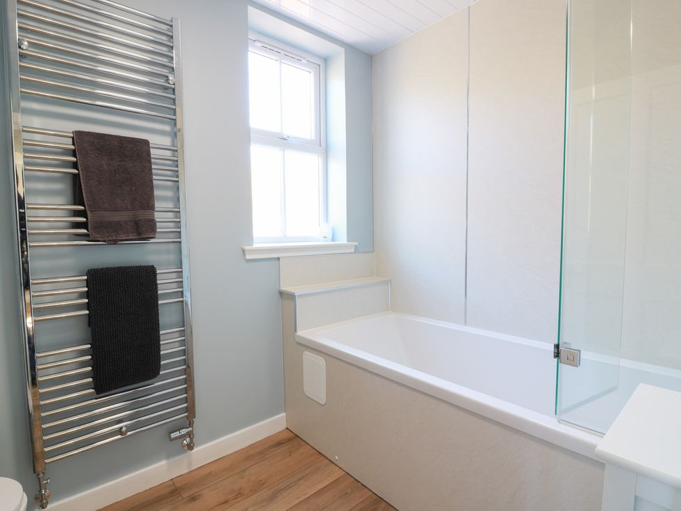 A bathroom with a bathtub and towel rail at Clayhills Cottage in Blairgowrie