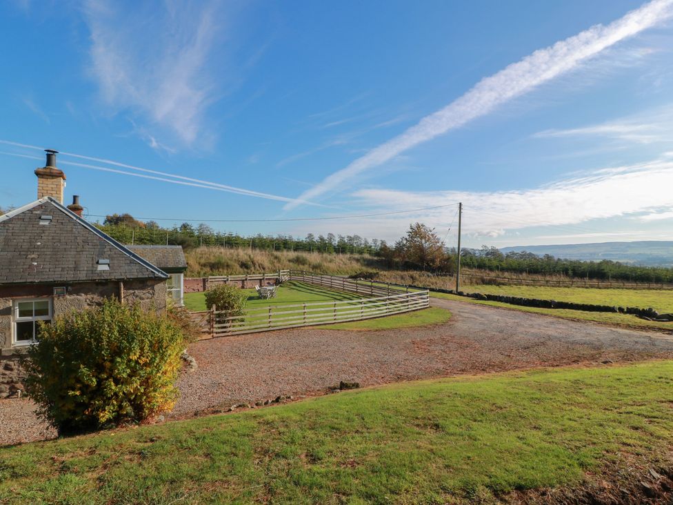 An outdoor area with a cottage and fenced field at Clayhills Cottage Blairgowrie
