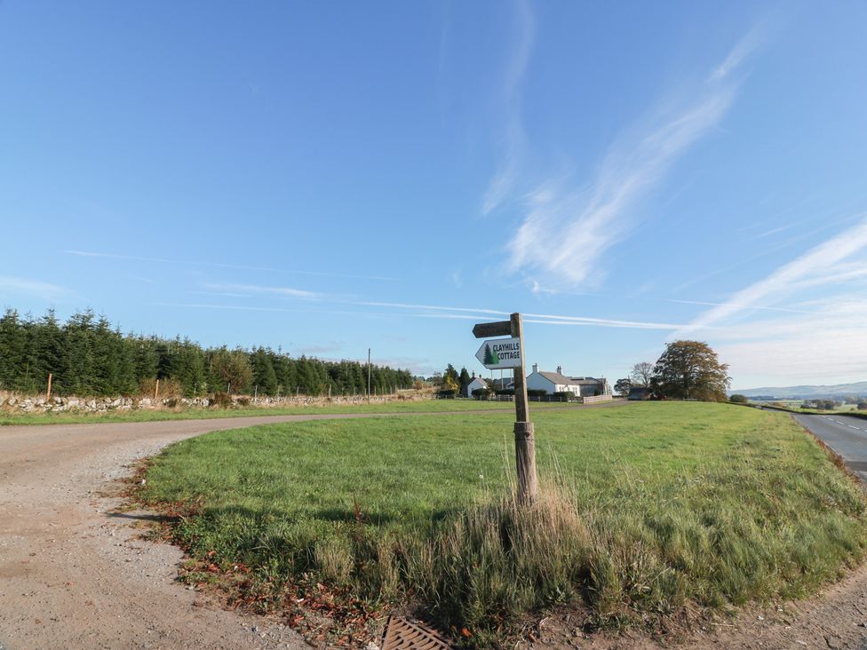 A signpost on a road with grass and trees at Clayhills Cottage in Blairgowrie