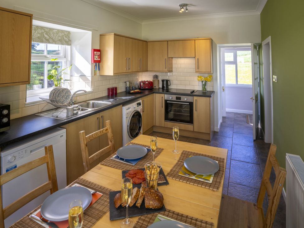 A kitchen with wooden cabinets and a dining table at Clayhills Cottage in Blairgowrie