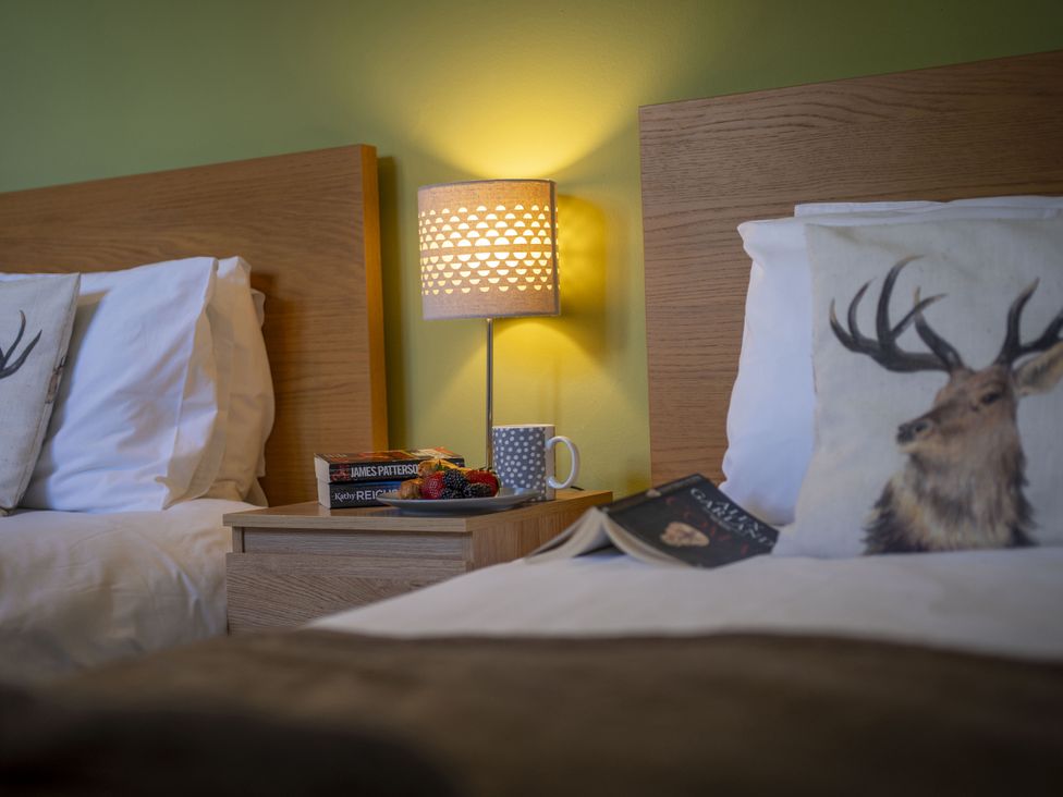 A bedroom with two beds and a bedside table at Clayhills Cottage in Blairgowrie