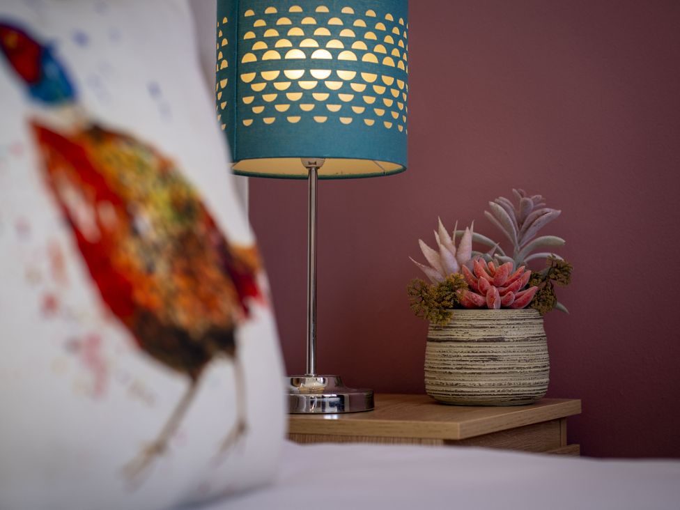 A side table with a lamp and potted plants at Clayhills Cottage Blairgowrie