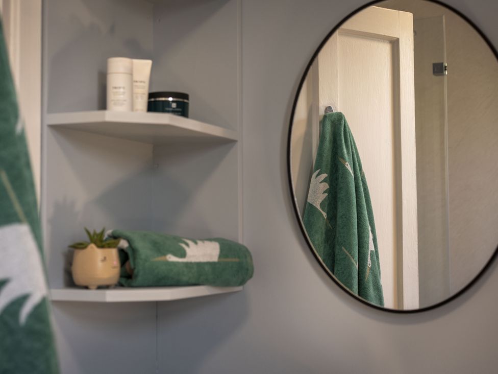 A bathroom with shelves containing skincare products and towels at Clayhills Cottage in Blairgowrie