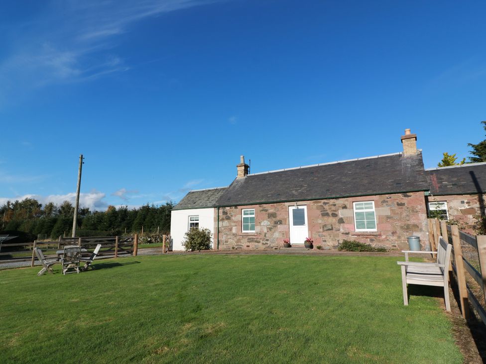 A cottage with a garden and chairs at The Bothy in Blairgowrie
