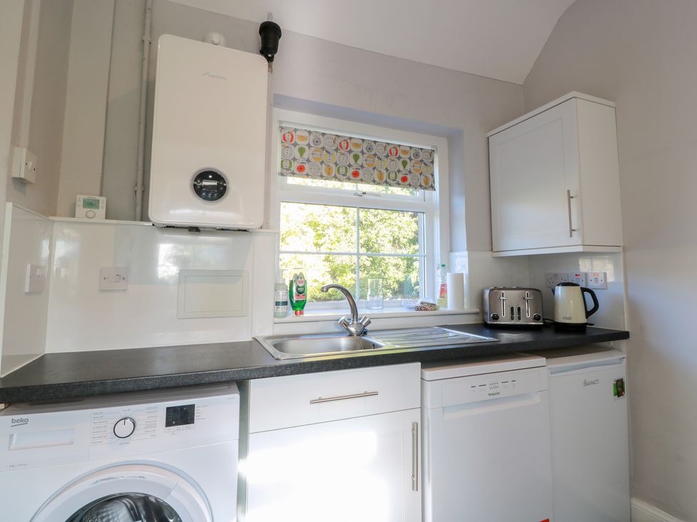 A kitchen with a sink, dishwasher, washing machine, kettle, and toaster at The Bothy in Blairgowrie