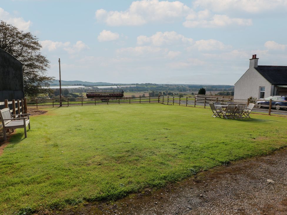A garden with grass, a bench, and a table with chairs at The Bothy in Blairgowrie