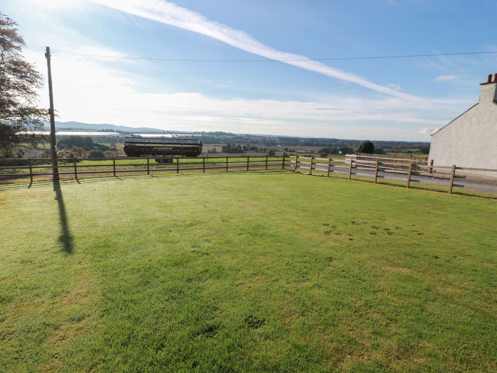 A grassy area with a fence and a tractor in view at The Bothy in Blairgowrie