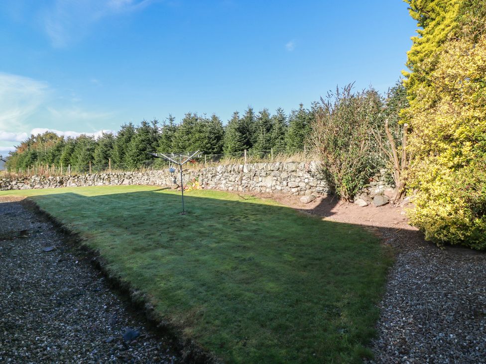 A garden with a clothesline and a stone wall at The Bothy in Blairgowrie