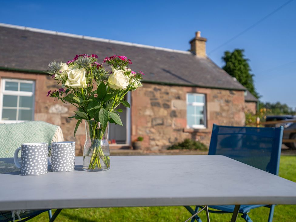 A table with flowers and mugs in an outdoor area at The Bothy in Blairgowrie